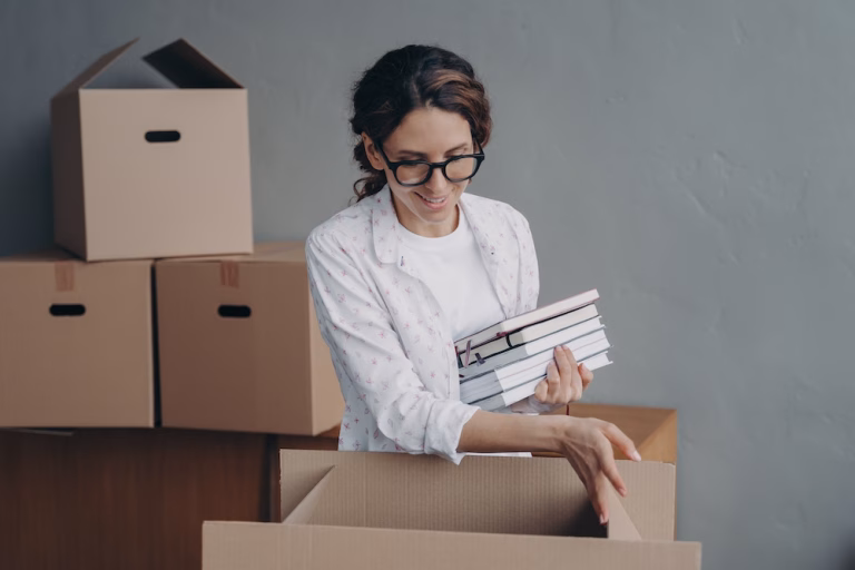 Hispanic female packing items in carton box on relocation day